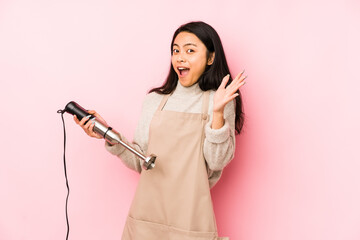 Young chinese woman holding a mixer isolated pointing to the side