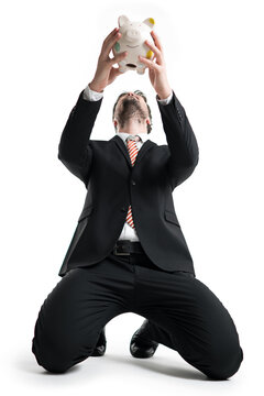 kneeing businessman holding a piggy-bank above his head in front of white background