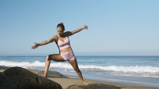 Girl doing yoga poses on a beach in sun - Goldy