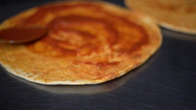 Hand putting tomato paste on a pizza basen 60fps slowmo
