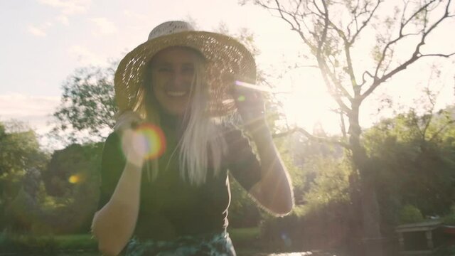 Cute young woman smiling out of pure happiness holding straw hat with light rays