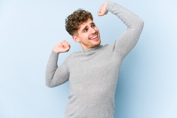 Young blond curly hair caucasian man isolated stretching arms, relaxed position.