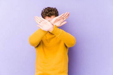 Young blond curly hair caucasian man isolated keeping two arms crossed, denial concept.