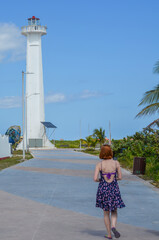 Mujer caminando en la playa con faro Mexico