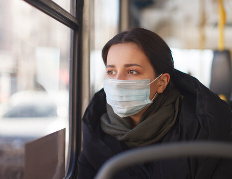 young woman with medical mask in city transport, bus, autumn clothing