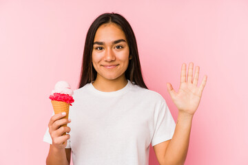 Young asian woman holding a ice cream isolated smiling cheerful showing number five with fingers.