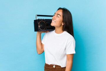 Young indian woman holding a vintage cassete isolated