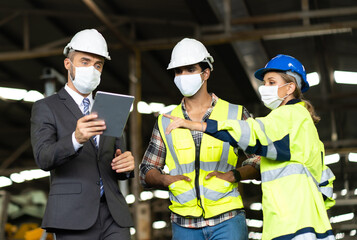 Engineers people are brainstorming solving problems of heavy industrial machinery. Worker man and asian woman wearing face mask prevent covid-19 virus and protective hard hat. .