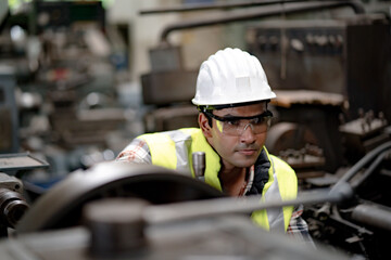 Man at work. Mechanical Engineer  man in Hard Hat Wearing Safety Jacket working in Heavy Industry Manufacturing Facility. Professional Engineer Operating lathe Machinery