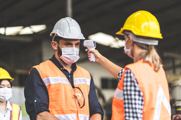 Fototapeta premium Temperature measurement with employee temperature meter before entering work at factory. Professional engineering team.