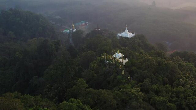 4K drone footage of Buddhism temple Thamma Park padoga on hill at sunrise in Ban Khao Na Nai village in Phanom, Surat Thani, Thailand