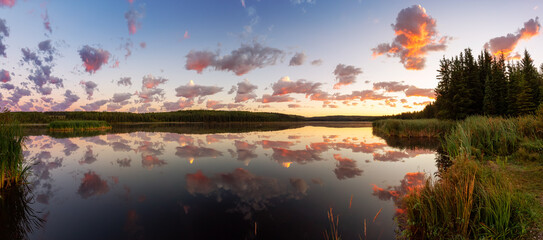 Beautiful Panoramic View of a Colorful Sunrise with Water Reflection at the Lake. Taken in Northern British Columbia, Canada. Nature Panorama Background