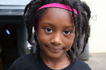 Cute young black girl wearing pink headband close up head shot