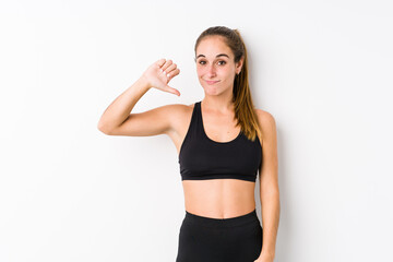 Fototapeta na wymiar Young caucasian fitness woman posing in a white background showing a dislike gesture, thumbs down. Disagreement concept.