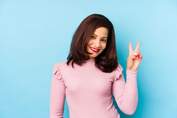 Middle age latin woman isolated joyful and carefree showing a peace symbol with fingers.