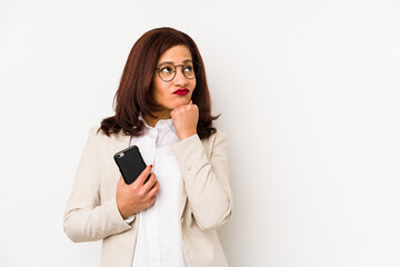 Middle age latin woman holding a mobile phone isolated looking sideways with doubtful and skeptical expression.