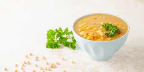 Pea soup with pieces of bacon and parsley in blue bowl on a white background.