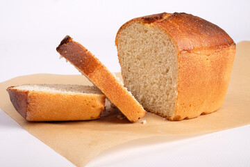 bakery products, freshly baked wheat bread, sliced bread on parchment paper isolated on white background