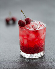 Cold alcoholic cocktail with cherry and ice cubes. Cherry Cocktail with Vodka. Selective focus