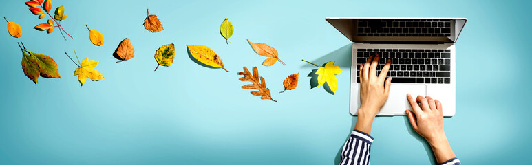 Autumn leaves with person using a laptop computer from above