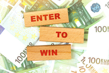 Against the background of euro bills, the text is written on wooden blocks - ENTER TO WIN