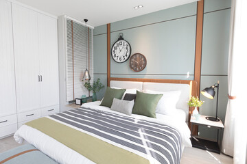 Modern green and brown bedroom with striped pattern. large wall clock on wall.