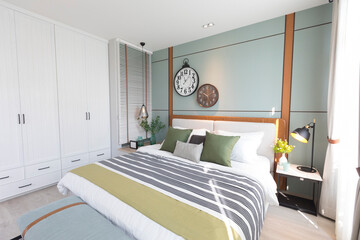 Modern green and brown bedroom with striped pattern. large wall clock on wall.