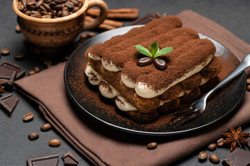 Classic tiramisu dessert on ceramic plate on dark concrete background