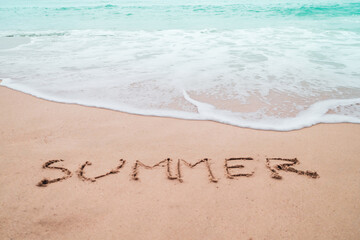 Summer word hand drawn on sand summer beach.