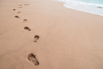 Human footprint on sand summer tropical beach background.