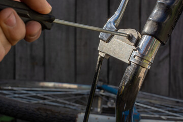 fixing an old rusty bike with a screwdriver; turns the screws with a screwdriver on the handlebar of an old bike, fixing the brakes