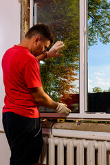 The worker inserts glass into the window frame, triple glazing of the plastic window, insulation...
