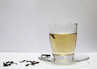 Hot tea in glass cup on white table.