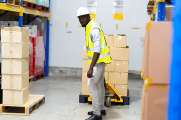 middle aged African American warehouse worker preparing a shipment in large warehouse distribution centre