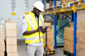 middle aged African American warehouse worker preparing a shipment in large warehouse distribution centre