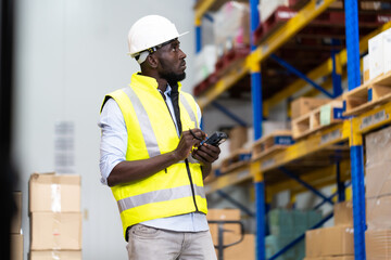 middle aged African American warehouse worker preparing a shipment in large warehouse distribution...