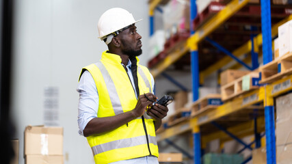 middle aged African American warehouse worker preparing a shipment in large warehouse distribution...