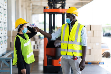 Temperature measurement with employee temperature meter before entering work at factory. Professional engineering team. Black people worker.