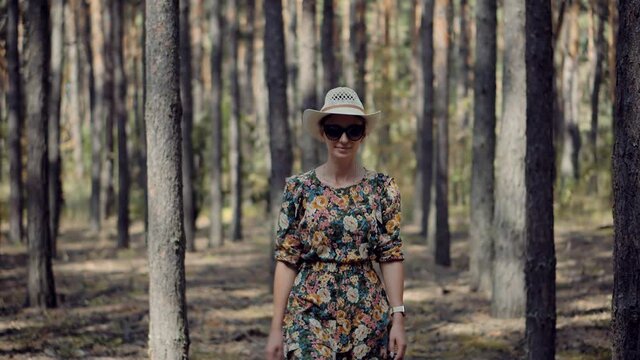 Holiday Vacation Tourist Journey Trip In Warm Day.Beautiful Healthy Girl In Dress Walking In Greenwood.Carefree Female Exploring Spruce Forest In Sunny Time.Active Woman In Hat Walking In Pine Forest.