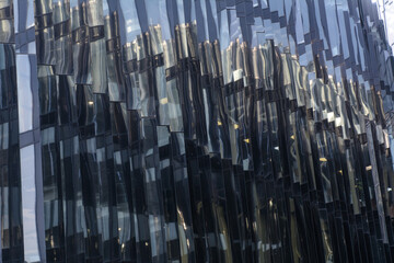 the modern facade of the building is made of glass and concrete with broken reflections. Concept-abstract background