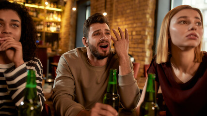 No Way. Close up of friends looking disappointed while watching sports match on TV together, drinking beer and cheering for team in the bar. People, leisure, friendship and entertainment concept