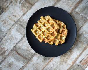 Vegetable waffles from zucchini and herbs on a dark plate close-up
