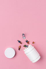 Miniature people coming out of pill box on pink background. Minimal pop art social life concept. Flat lay.