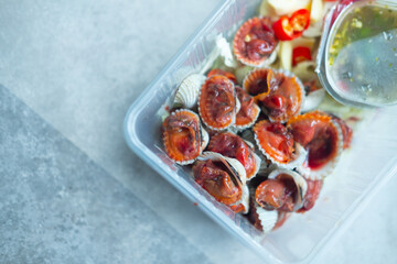 Boiled cockles with hot and spicy seafood sauce in box. Local menu from sea shell. Semi-cooked raw food