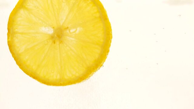 Lemon floats in water with bubbles on a white background. Lemon slice in a glass close-up. 