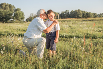 Naklejka na ściany i meble Happy child with Grandfather playing at the meadow. Grandpa retiree. Retirement parent