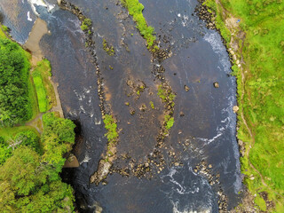 Small river flows by a green fields, West of Ireland, Aerial top down view.