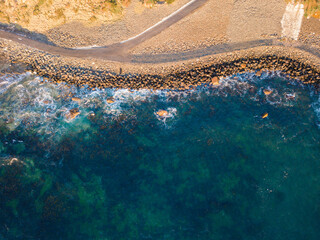 Aerial view of a beach with rock on the shore.