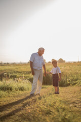 Fototapeta na wymiar Happy senior man Grandfather with cute little boy grandson playing in field.