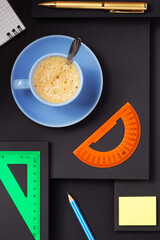 office supplies and cup of coffee at black background